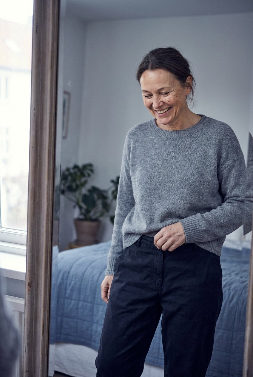 Woman smiling as she checks her looser waistband at home