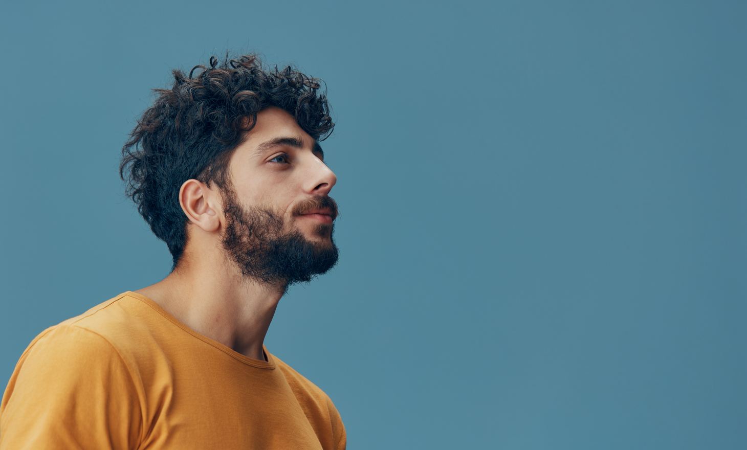Man with curly hair looking upward against a calm backdrop